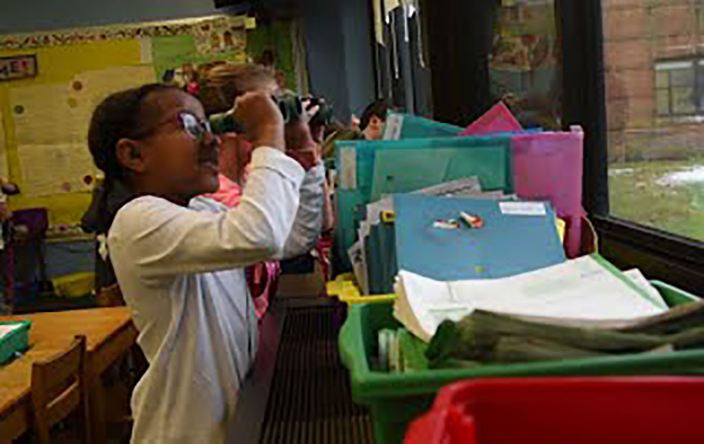 Students looking out the window using binoculars