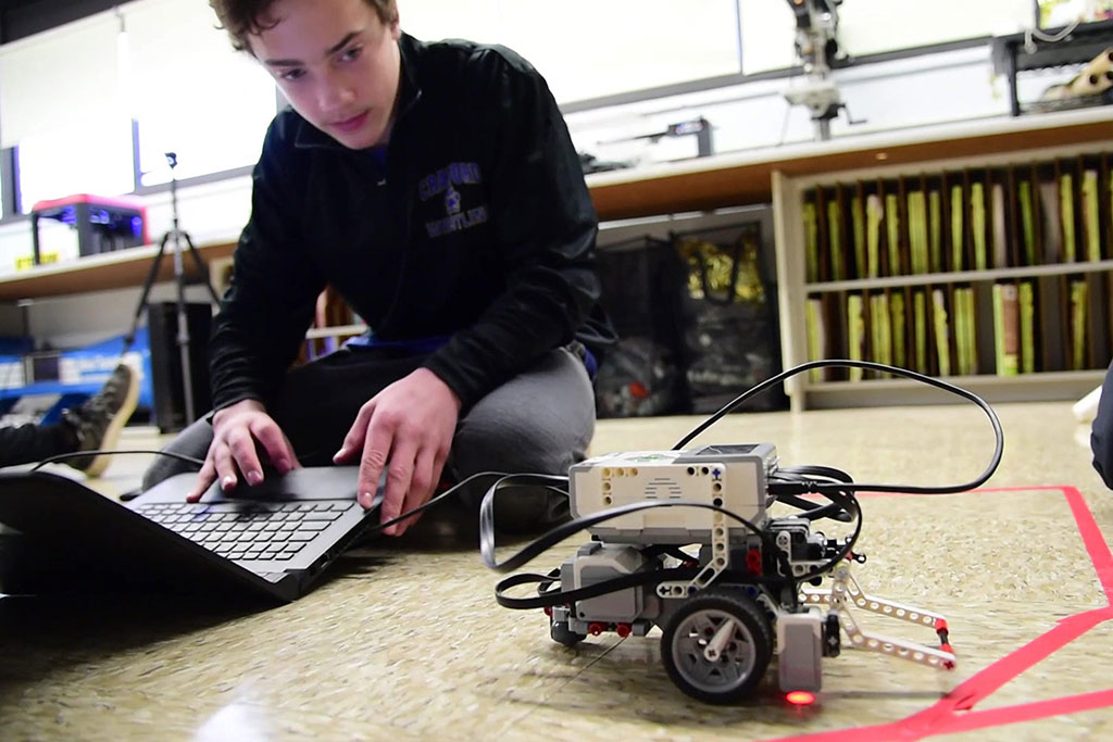 A student working on their computer to control a robot